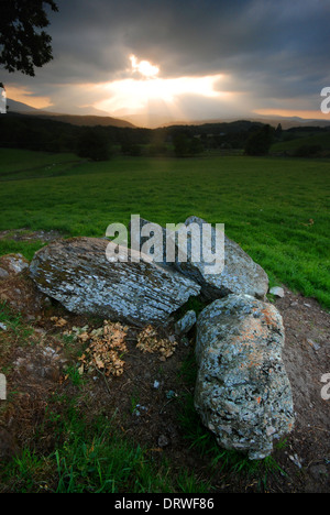 Rocce nel Galles del Nord, con lo scoppio di sole attraverso le nuvole sopra il Snowdonia mountain range dietro Foto Stock