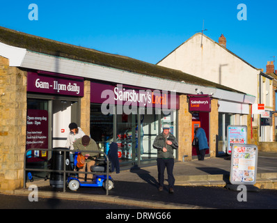 Gli acquirenti anziani al di fuori di un villaggio Sainsbury's supermercato locale convenience store Foto Stock