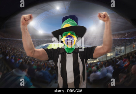 Un brasiliano tifoso di celebrare un obiettivo in uno stadio di calcio. Foto Stock