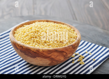 Couscous crudo in ciotola di legno su sfondo di legno closeup Foto Stock