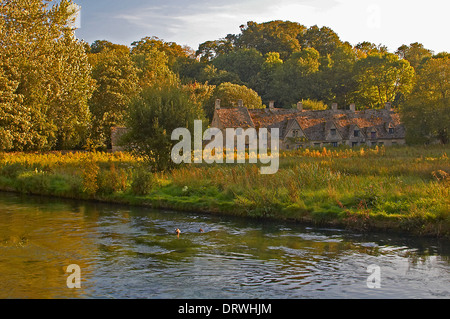 Villaggio di Cottswold di Bibury e il fiume Coln, cottage di Arlington Row e la riserva naturale di rack Isle in una serata estiva. Foto Stock