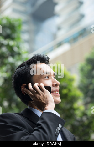 Cinese uomo business utilizzando il suo telefono cellulare all'aperto nella moderna città asiatiche. Foto Stock