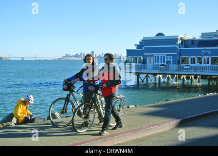 Amici a piedi il loro noleggio bici su Sausalito marciapiede lungo la baia Foto Stock