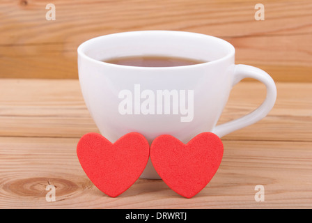 Tazza di tè e due cuori rossi. Foto Stock