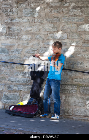 Ragazzo suona il violino. Musicista di strada. Strade di Tallinn in Estonia. Foto Stock