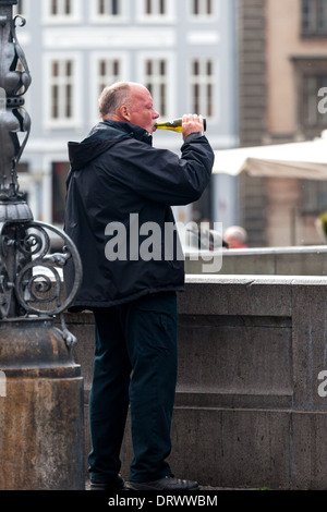 Uomo di bere dalla bottiglia di birra sulle strade di Copenhagen Danimarca (.old town area ). Foto Stock