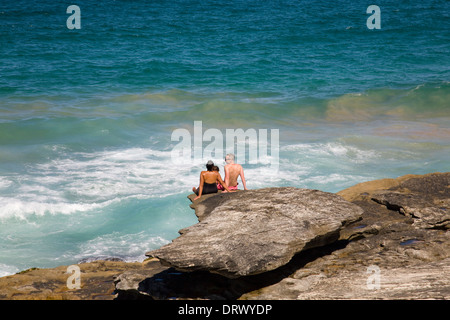 Famiglia seduti sulle rocce al sud Curl Curl beach, uno di Sydney la famosa Northern Beaches, Nuovo Galles del Sud, Australia Foto Stock