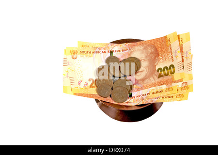 Isolato a sud africana di banconote e monete in recipiente di rame su sfondo bianco Foto Stock
