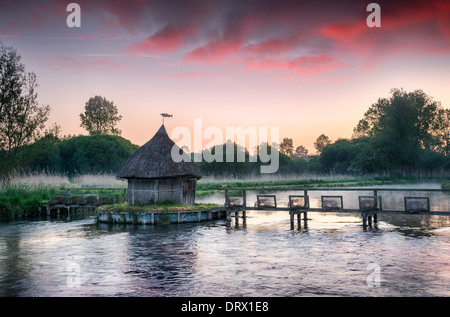 Con il tetto di paglia del pescatore e capanna tradizionale trappole di anguilla sul fiume Test in Hampshire Foto Stock