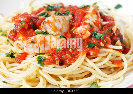 Pesce fresco in salsa arrabbiata, servita su spaghetti, sprinked con il prezzemolo guarnire, primo piano Foto Stock