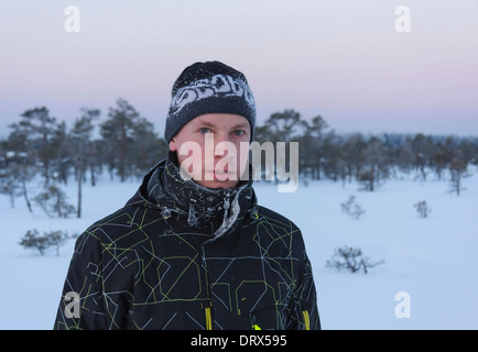 Ritratto di un giovane uomo con il pupazzo di neve i vestiti e il cappello in una palude presto nel mattino invernale Foto Stock