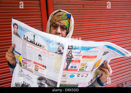 Uomo musulmano la lettura di un quotidiano nella Vecchia Delhi, India Foto Stock