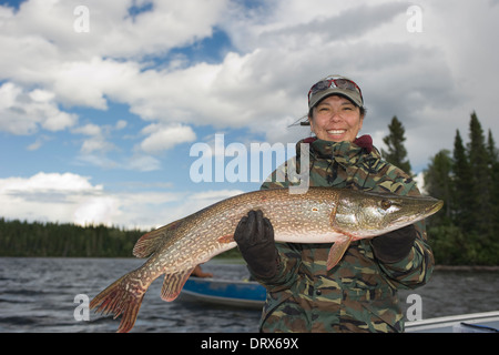 Donna pescatore tenendo in mano un grosso luccio del nord ha catturato da una barca sul lago nel nord Ontario, Canada Foto Stock