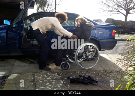 Regno Unito west sussex una donna anziana essendo aiutato dal caregiver ad entrare in una macchina Foto Stock