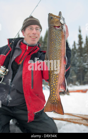 Pescatore sorregge un inverno brook trota pescata pesca sul ghiaccio. Foto Stock