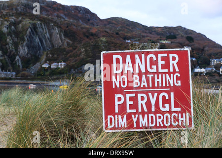 Una spia rossa segno legge 'Drabbia n' balneare e in gallese "Perygl Dim Ymdrochi' a Fairbourne sulla mezza costa del Galles Foto Stock