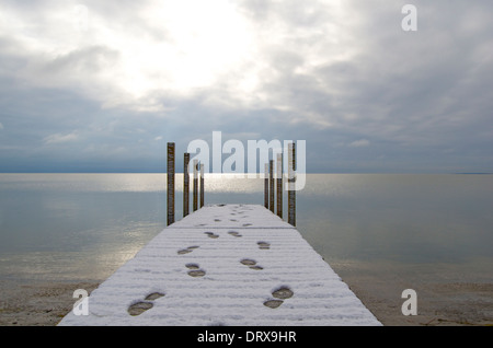 Dock con superficie nevosa e impronte umane che conducono fuori e indietro Foto Stock