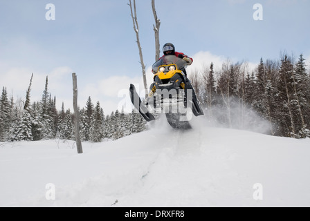 Un uomo snowmobiling su un sentiero nella parte posteriore paese d'inverno. Foto Stock