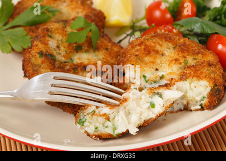 Facile fare fishcakes, con pesce al vapore sgranate in purea di patate e prezzemolo e mescolare, servito con insalata Foto Stock