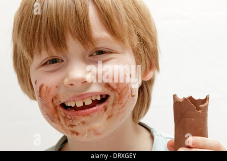 Ritratto di un felice ragazzo giovane mangiare il cioccolato Foto Stock