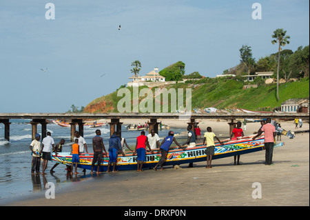 Gli uomini tirando in una piroga di pesca, Bakau, Banjul (Gambia Foto Stock