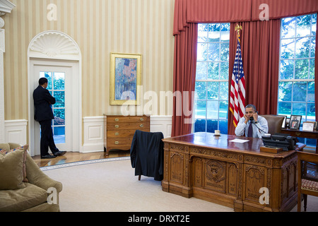 Il Presidente Usa Barack Obama parla al telefono con il Senato leader della minoranza Mitch McConnell come Rob Nabors, vice capo di Stato Maggiore per la politica, si erge dalla nell'Ufficio Ovale della Casa Bianca Ottobre 14, 2013 a Washington, DC. Foto Stock