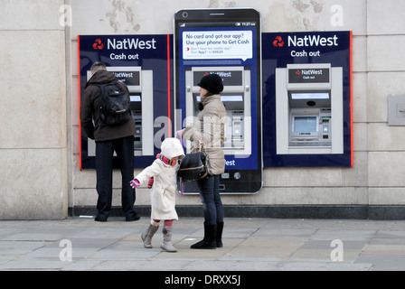 Londra, Inghilterra, Regno Unito. Nat West distributori automatici di contante - uomo ottenere contanti, donna e bambino in attesa [2 foto in formato digitale fuse] Foto Stock