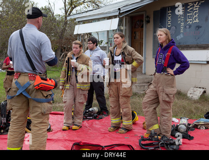 Donne studenti dalla scuola di alta formazione antincendio classe ascoltare istruttore prima esercitazione in casa abbandonata Foto Stock