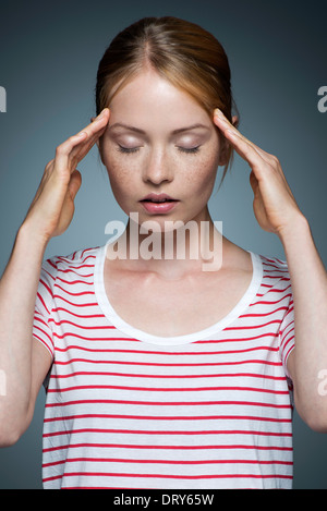 Giovane donna premendo i lati della testa Foto Stock