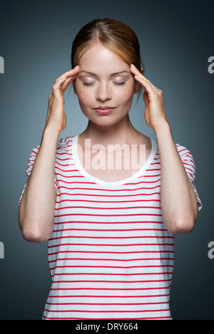 Giovane donna tenendo i lati della testa Foto Stock