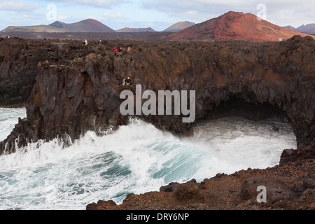 I turisti in una visualizzazione di balcone al di sopra di una grande onda schiantarsi contro scogliere sul mare a Costa Los Hervideros Lanzarote isole Canarie Foto Stock