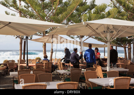 Persone sotto gli ombrelloni in un ristorante sul mare in El Golfo, Lanzarote, Isole Canarie, Spagna Foto Stock