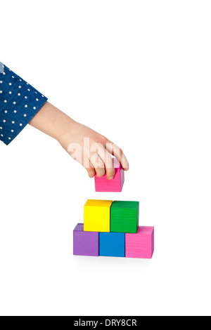 Bambino la mano la costruzione di una torre in mattoni isolati su sfondo bianco Foto Stock