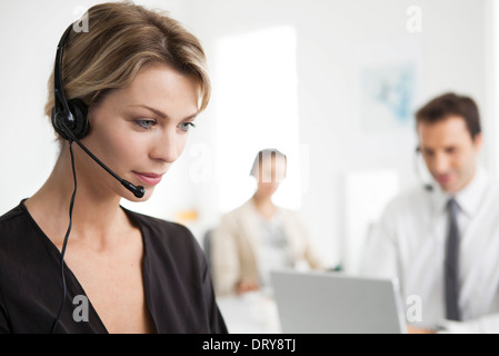 Imprenditrice che indossa la cuffia lavoro in ufficio Foto Stock