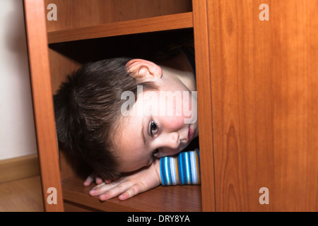 Paura bambino ragazzo nascosto in un armadio Foto Stock