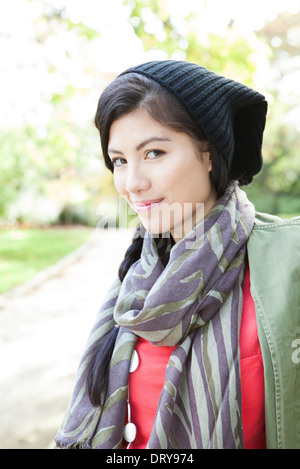 Giovane donna indossa cappello in maglia e sciarpa, sorridente, ritratto Foto Stock