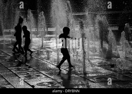 Sagome di bambini che giocano in acqua delle fontane. Foto Stock