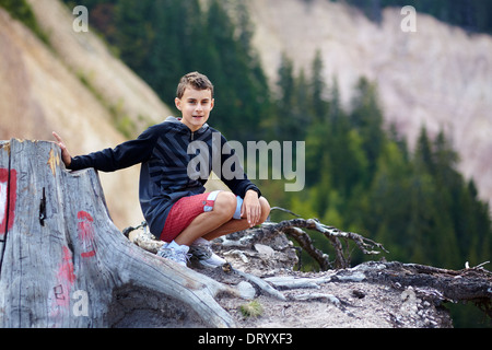 Ragazzo seduto vicino a una marcata tronco di albero su una escursione sentiero in Ruginoasa Pit, Apuseni montagne Foto Stock