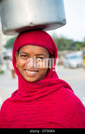 Poveri di casta inferiore Indian ragazza adolescente che porta un piatto di riso sul suo capo. Andhra Pradesh, India Foto Stock