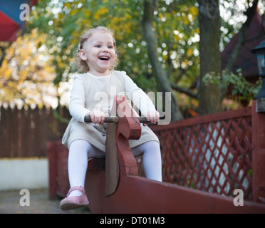 Carino bambina swinging presso il parco giochi Foto Stock