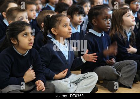 I bambini di una scuola insieme cantando e battendo le mani ed esecuzione di azioni Foto Stock