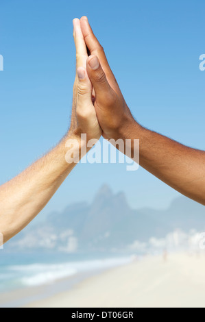 Diversità brasiliana interracial mani cooperando insieme la spiaggia di Ipanema di Rio de Janeiro in Brasile Foto Stock