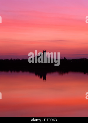 Una silhouette e immagine speculare della Cattedrale di Ely, Cambridgeshire, dopo il tramonto, cercando W sul Fiume Great Ouse riflettendo il colore rosso intenso del cielo. Foto Stock