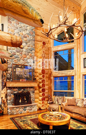 La grande sala in un moderno log cabin, con decorazioni rustiche e mobili. Foto Stock