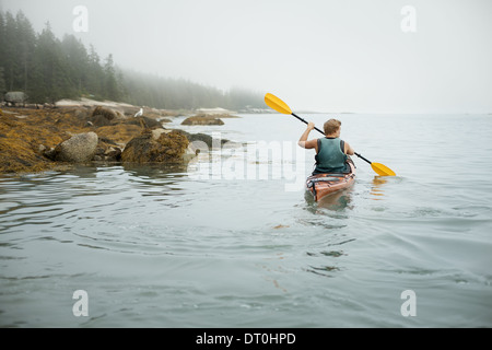 Lo stato di New York STATI UNITI D'AMERICA uomo canoa kayak su acqua calma misty condizioni Foto Stock