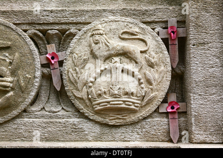 Papaveri della Royal Legion su croci di legno e scudo in pietra intagliata dell'esercito britannico sul lato del Cenotaph War Memorial a Bristol, in Inghilterra Foto Stock