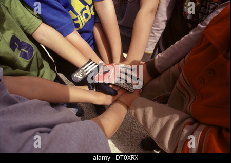 Ebrei israeliani e arabi di bambini mettere le mani insieme prima del gioco del calcio nel parco giochi cortile di "Mano nella mano" integrato, bilingue scuola Hebrew-Arabic per ebrei e arabi di bambini situato nella parte ovest di Gerusalemme Israele Foto Stock