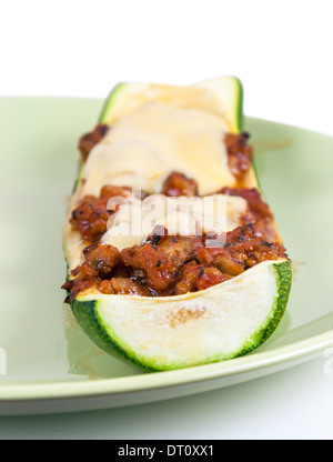 Primo piano di zucchine ripiene di carne macinata e formaggio sulla piastra verde Foto Stock