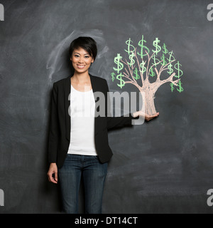 Felice Asian Business donna di fronte a Chalk money tree disegno sulla lavagna. Foto Stock