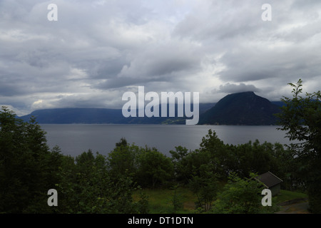 Le nuvole di tempesta coprono le montagne di Hardangerfjord nella contea di Hordaland, Norvegia. Foto Stock